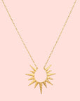 The 16" North Star Burst Necklace features a delicate chain and a sunburst-shaped pendant with pointed rays radiating from a central teardrop, all finished in textured, hammered 18kt gold plate for added charm.