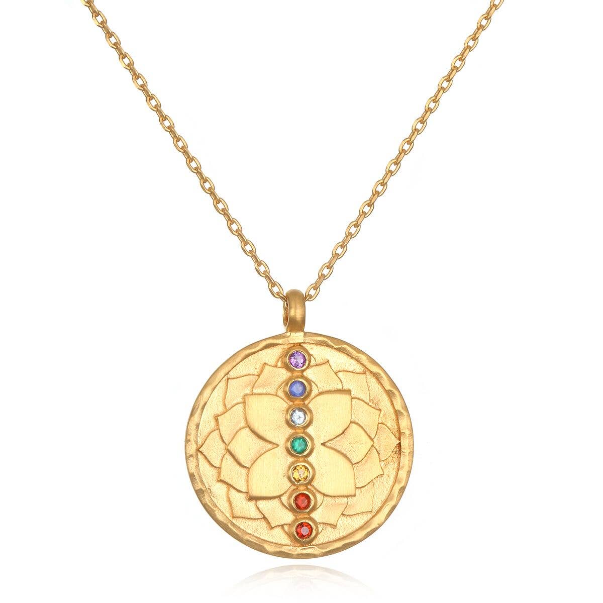 The Satya Jewelry Multi Stone Chakra Necklace features a round 18k gold plated pendant with a lotus design and seven vertically arranged semi-precious gemstones symbolizing chakra alignment.
