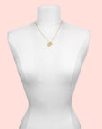 The Blue Topaz Sun Pendant Necklace is a gold-plated piece with a round blue topaz pendant, shown on a white dress form mannequin against a plain background.
