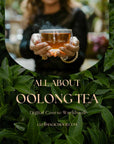 A person holds a steaming glass of Oolong tea above green tea leaves. Text: "All About Oolong: A Digital Coursebook. clubmagichour.com." Ideal for aspiring tea connoisseurs.