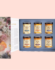 The "Once Upon a Hive" - Blossom to Bottle gift box showcases six jars of premium honey in two neat rows, each with unique labels. The lid's floral images beautifully contrast the soft pink background, reflecting the dedication of skilled beekeepers.