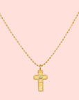 The 16" Emerald Dot Cross Pendant Necklace with a 3" extension features a beaded chain and a textured cross pendant accented by a small emerald, shown on a white background—a timeless piece of faith jewelry.