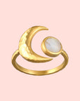 The Cradled in Light Moonstone Ring is a gold plated piece featuring a crescent moon and a round iridescent moonstone set side by side, shown on a plain white background.