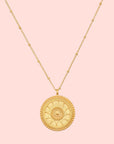 The 18" Sunburst Medallion Necklace is a gold-plated piece featuring a circular sun, moon, and star pendant—perfect for adding celestial charm to any look.
