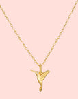 The Loving Devotion Hummingbird Necklace 16" features a detailed pendant on a gold chain, highlighted by a sparkling white topaz accent for the bird's eye and finished in 18k gold plating.
