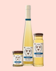 Three containers of Savannah Bee Co. Honey - Acacia are displayed against a peach background: a small jar, medium bottle, and tall bottle feature bee-designed labels with the text "Raw Acacia Honey," emphasizing its single-varietal nature.