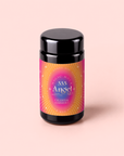 A black jar featuring a vibrant pink, purple, and gold label reading “555: Celestial Harmony: Papaya-Mango-Rose Tea with Ashwagandha” rests on a pale pink background—perfect for anyone seeking stress relief through an ashwagandha-infused herbal tea blend.