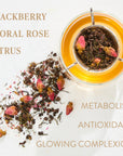 A glass cup filled with tea has a metal infuser containing Magic Hour's Aries - Garden of Eden Oolong loose leaf tea and rose buds. Dried tea leaves and rose petals are scattered beside the cup. Text reads: "BLACKBERRY, FLORAL, ROSE, CITRUS, METABOLISM, ANTIOXIDANT, GLOWING COMPLEXION.