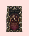 Presented in a decorative package labeled "Artemis of the Wilds: Wild Moon White Tea," this enchanting low-caffeine tea features a golden archer and floral designs set against a black background with pink accents. Savor the smooth, delicate flavors of moon white tea in every magical cup.