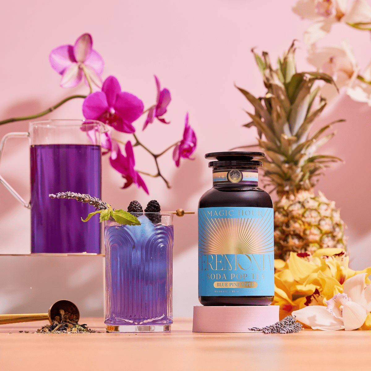 A vibrant scene featuring Blue Pineapple: Ceremonial Soda Pop Tea—an antioxidant-rich purple drink with Butterfly Pea Flower, served in a glass and pitcher, surrounded by orchids, pineapple, and yellow flowers.