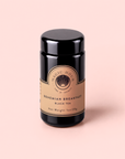 A black canister of Magic Hour Bohemian Breakfast Vanilla Puerh Black Tea for Digestion & Energy is set against a pale pink background. The beige label with gold details displays the product name and weight of 1oz (28g), making it an elegant coffee alternative for your morning ritual.