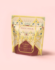 The "Pumpkin Spice Chocolate Truffle" herbal tea comes in a decorative yellow and maroon resealable pouch labeled "Magic Hour," featuring stylized patterns on a pale pink background. This caffeine-free blend offers an elegant, intricate design.