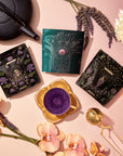 A Cycle Harmony Tea Sampler Set featuring three pouches of adaptogenic tea arranged around an empty teacup, accompanied by a teapot, a tea infuser, lavender sprigs, and flowers for hormonal harmony.