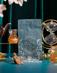 The Divine Timing Calm plaque, featuring gold designs and the words “Calm, Divine Timing, Rest & Trust, Answers and Prayers,” stands on a teal table with teacups, a teapot, an hourglass, and flowers against a green background.