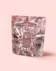 A stand-up pouch with a geometric diamond pattern on light pink, featuring the label “Diamond - Champagne & Strawberry Jasmine White Tea for Beautiful Skin” in white text within a central oval frame.