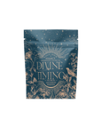 A blue resealable pouch labeled “Divine Timing Balance” features gold celestial and botanical designs, including flowers, birds, and stars. The tea package highlights “Magic Hour Balance Fermentation Wellness Tea.”.