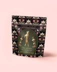 A decorative black and gold tea package labeled "Freya The Radiant: Jasmine Bai Hao Oolong with Bergamot & Berry." The front displays an elegant female figure, floral patterns, and radiant details.