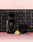 The Gemini Astrology Tea Gift Set includes a black and gold "Magic Hour" box, matching "Gemini" tea jar, tea infuser, and "Opal Moon Ritual Tea" sachet, elegantly arranged on a pink gradient background.