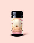A black tea canister labeled “Tea for Abundance: Goddess Green: Apricot & Lychee Green Tea,” adorned with sun and floral designs on a peach background. This blend features apricot and lychee green tea artfully combined with organic lemongrass, crafted to nourish the solar plexus chakra.
