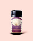 A black tea canister labeled "Tea for Inspiration: Amethyst: Strawberry Passion Fruit Herbal Tea Blend," featuring the third eye chakra and organic herbal ingredients designed to enhance spiritual clarity, is set against a light pink background.