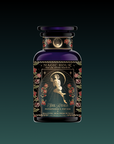 A dark, ornate bottle from the Monthly Magic Tea Subscription Box labeled "Magic Hour, Persephone’s Potion," features a woman amid roses and gold stars, celestial designs, “She Rises,” and honors goddess tea rituals.
