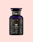 A dark purple apothecary-style bottle labeled "Goddess of Earl: Lavender London Fog- Tea for Blooming Clarity & Calm Moods" with gold accents and intricate designs, set against a pale pink background. Inspired by calming tea and Lavender Earl Grey notes.