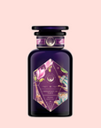 A dark purple canister labeled “Breakfast in Paris—Oolong Black Tea Scented with Fruits & Flowers of Secret Parisian Gardens” features gold and pink accents, floral designs, the Eiffel Tower, and a butterfly on a pale blush background.