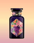 A dark purple glass bottle with a geometric label featuring colorful fruit, flower, and leaf illustrations against a peach-to-pink gradient—perfect for Pink Moment Pixie - Hibiscus Tangerine Dream Herbal Tea.