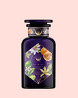 A dark purple glass bottle with a decorative label of leaves, flowers, and fruit highlights the "Romance in Ravello - Chocolate-Passionfruit-Rose-Cream White Tea," set against a light pink background.