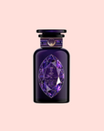 A faceted, gem-like bottle with gold accents, inspired by spiritual wellness, holds Amethyst: Strawberry-Passionfruit Gemstone Wellness Tea and stands out against a pale pink background.