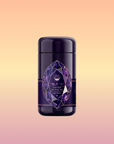 A dark purple tea canister with a geometric amethyst design label stands against a peach-to-yellow background. The label reads “Amethyst: Strawberry-Passionfruit Gemstone Wellness Tea”—herbal tea for clarity and balance.