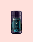 A dark purple cylindrical tea canister with a blue gemstone-shaped label displaying "Aquamarine Dream - Soothing Herbal Ayurvedic Adrenal Tonic" sits against a soft pink background.