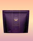 A purple "Aquamarine Dream - Soothing Herbal Ayurvedic Adrenal Tonic" tea bag features gold celestial designs and text on a pink-orange gradient background—the ideal calming sleep tea.