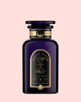 A dark purple glass bottle with black and gold label reads "Magic Hour" and "Bohemian Breakfast Vanilla Puerh Black Tea for Digestion & Energy," featuring an hourglass illustration, displayed on a plain light pink background as a coffee alternative.