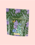 A green tea package featuring lavender, blueberries, mint leaves, and butterflies. The label reads “Blueberry Lavender Mint: Cosmic Garden Iced Tea,” a sugar-free, antioxidant-rich iced tea from Magic Hour.