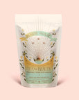 A pastel-toned pouch labeled “Tea for Beauty: Renewal: Peach, Goji & Rose Oolong Tea” features floral patterns, gold accents, and an egg illustration. The packaging details a ceremonial oolong tea blended with juicy goji berries and rose, emphasizing renewal and love.