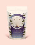 A pastel-colored pouch labeled "Tea for Intuition: 1111: Pineapple & Butterfly Pea Flower Herbal Tea" features celestial and floral designs. This enchanting blend combines pineapple, butterfly pea flower, and blue lotus to support the crown chakra. Net weight 1.5 oz (42g).