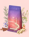 The Kapha: Caffeine-Free Saffron Spice Tea package features a yoga pose silhouette and is surrounded by cinnamon sticks, ginger, saffron, orange, and herbs, highlighting its vibrant Ayurvedic blend for evening balance.