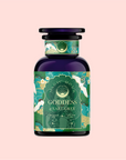A dark purple bottle labeled "London Fog Green" from Magic Hour features ornate patterns with peacocks, showcasing a green, gold, and blue color scheme against a light pink background. The hint of lavender beautifully complements the bergamot notes.