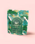 A vibrant tea package labeled “London Fog Green” stands upright on a pale pink background, adorned with green nature motifs and white cranes. The packaging highlights bergamot and lavender notes, and also features "Goddess of Earl Grey.