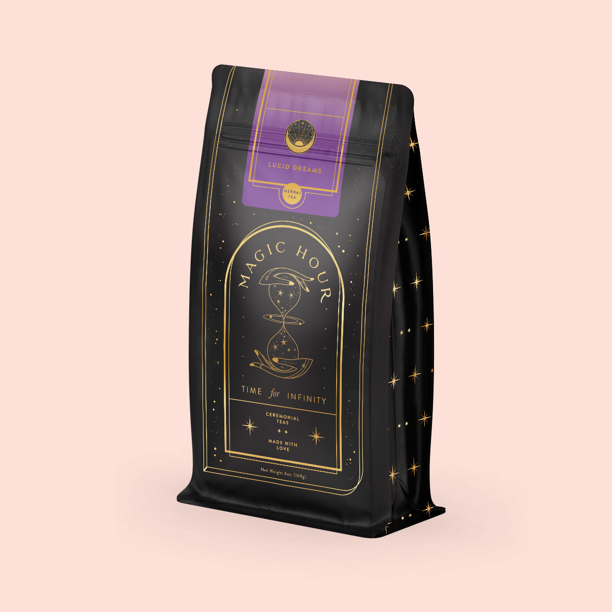 The "Lucid Dreams" Herbal Tea Refill Pouch is a black, gold, and purple bag of Magic Hour turmeric tulsi tea with an elegant hourglass and celestial design. The label reads "Lucid Dreams" and "Time for Infinity." This caffeine-free blend stands against a light beige background.