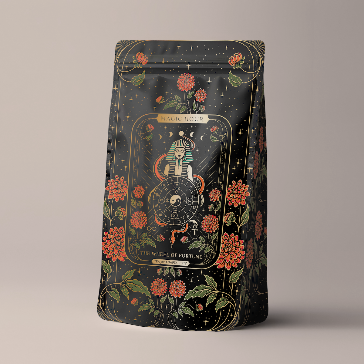 A black coffee bag intricately designed with gold and red floral patterns. At its center is an illustration of a mystical figure holding a wheel, alongside the text "Magic Hour" and "The Wheel of Fortune." The background showcases an array of stars and celestial motifs.