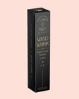 Image of a black rectangular box with gold text and designs. The box reads "Magic Hour" at the top, with an hourglass illustration. Below, it says "Wand Whisk: Rechargeable Stainless Steel Eco-Frother" and "for Perfectly Frothed Tea Lattes." Additional text and branding details are also visible. The organic tea box stands against a pale pink background.