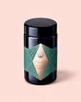 A dark glass jar with a green and gold geometric label reading “1111” and “ceremonial wellness” stands against a pale pink background, reflecting the premium tradition of Matcha 1111 : Highest Grade of Ceremonial Matcha.