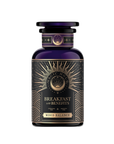 A dark, elegant jar labeled "Mood Balance: Breakfast with Benefits" features gold and white accents with sunburst patterns and wave motifs, suggesting the calming effect of Ashwagandha root for tranquility in every sip of this herbal tea.