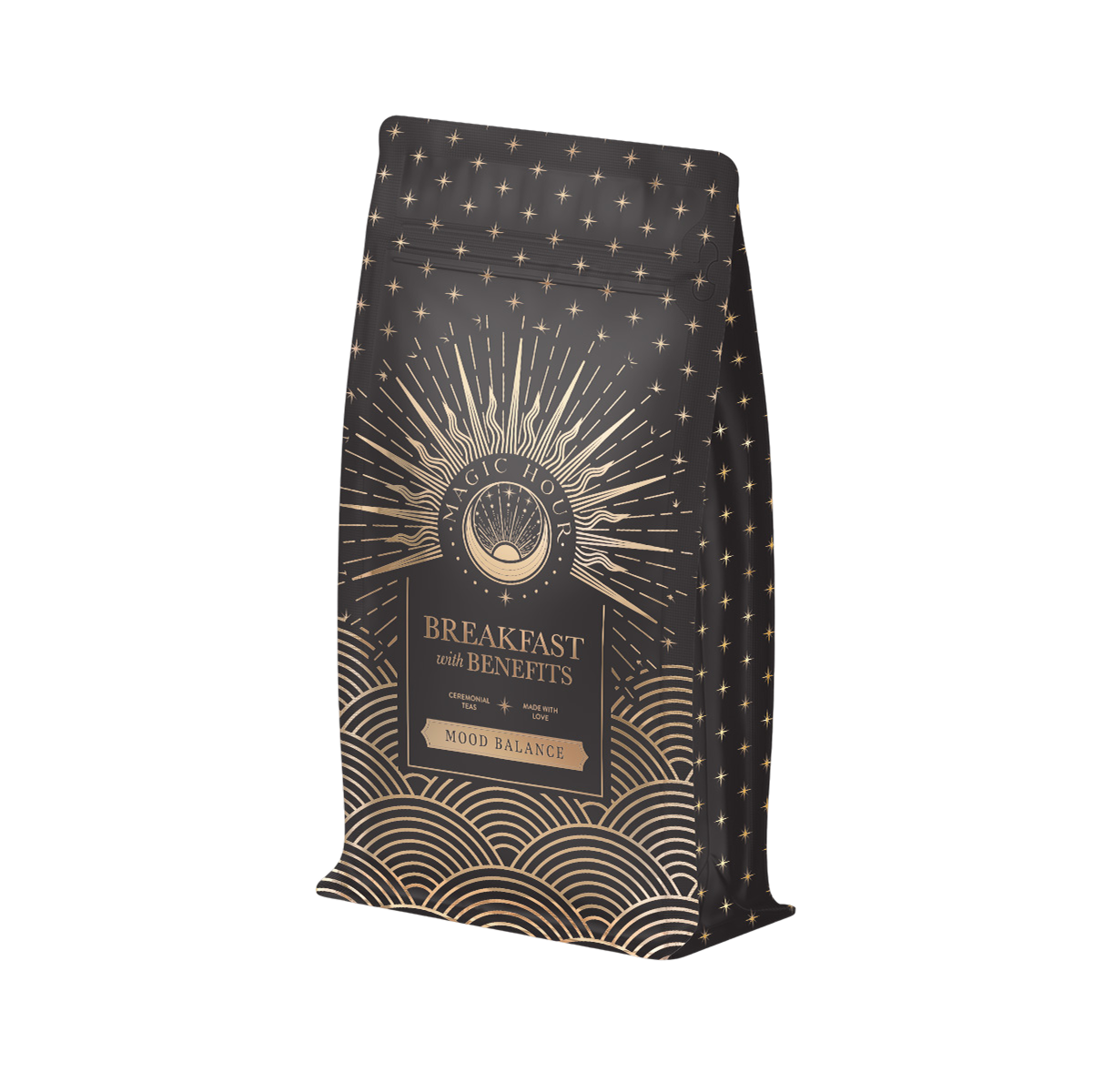 The "Mood Balance: Breakfast with Benefits" coffee bag in black and gold displays intricate geometric patterns and the text "Magic Hour" on a central design, enriched with ashwagandha root for a revitalizing touch.