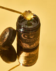 A jar of Moonflower Honey with a golden spoon lifting the antioxidant-rich honey. The celestial-designed jar and lid enhance its golden tones against a warm, bright yellow background.