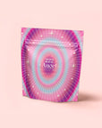 A pink and purple resealable pouch labeled "222: Hibiscus-Papaya Oolong with Roses" with star and ray designs stands upright on a light pink background, its celestial-themed packaging hinting at a soothing rose-infused blend.