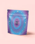 A purple-blue gradient pouch with starbursts and "444 Angel Frequency Aid Sachets Prosperity" in white text showcases 444: Sachiel's Prosperity—an apple-berry herbal tea with butterfly pea flower and blue spirulina—on a light pink background.