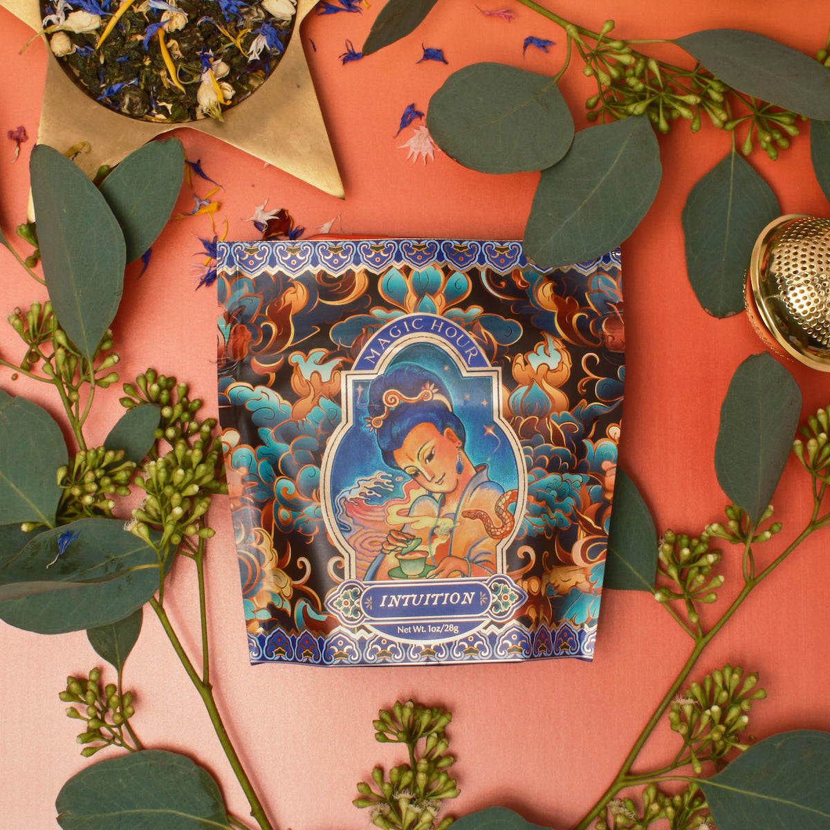 A vibrantly designed tea package labeled "Nuwa Tea for Intuition: Dragon Yuzu Oolong Case Packs" by Magic Hour is surrounded by eucalyptus leaves, flowers, and a star-shaped bowl of Organic Dragon Phoenix Jasmine Pearls. The background features a warm gradient of orange to red, creating an inviting atmosphere.